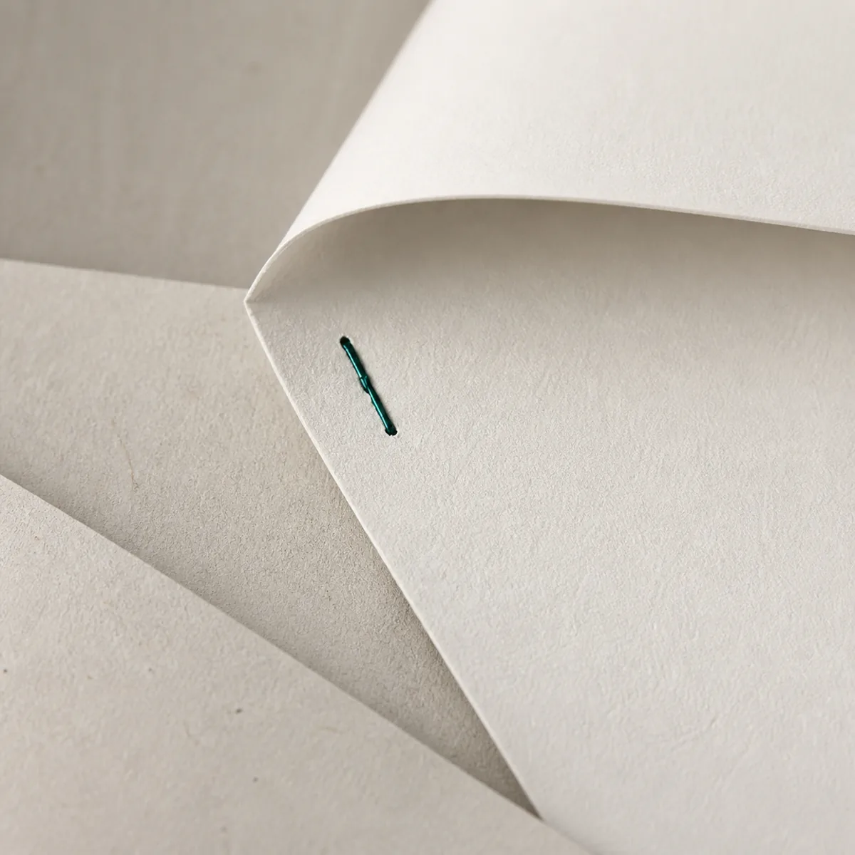 A heavy engagement document folded and secured with a teal staple.